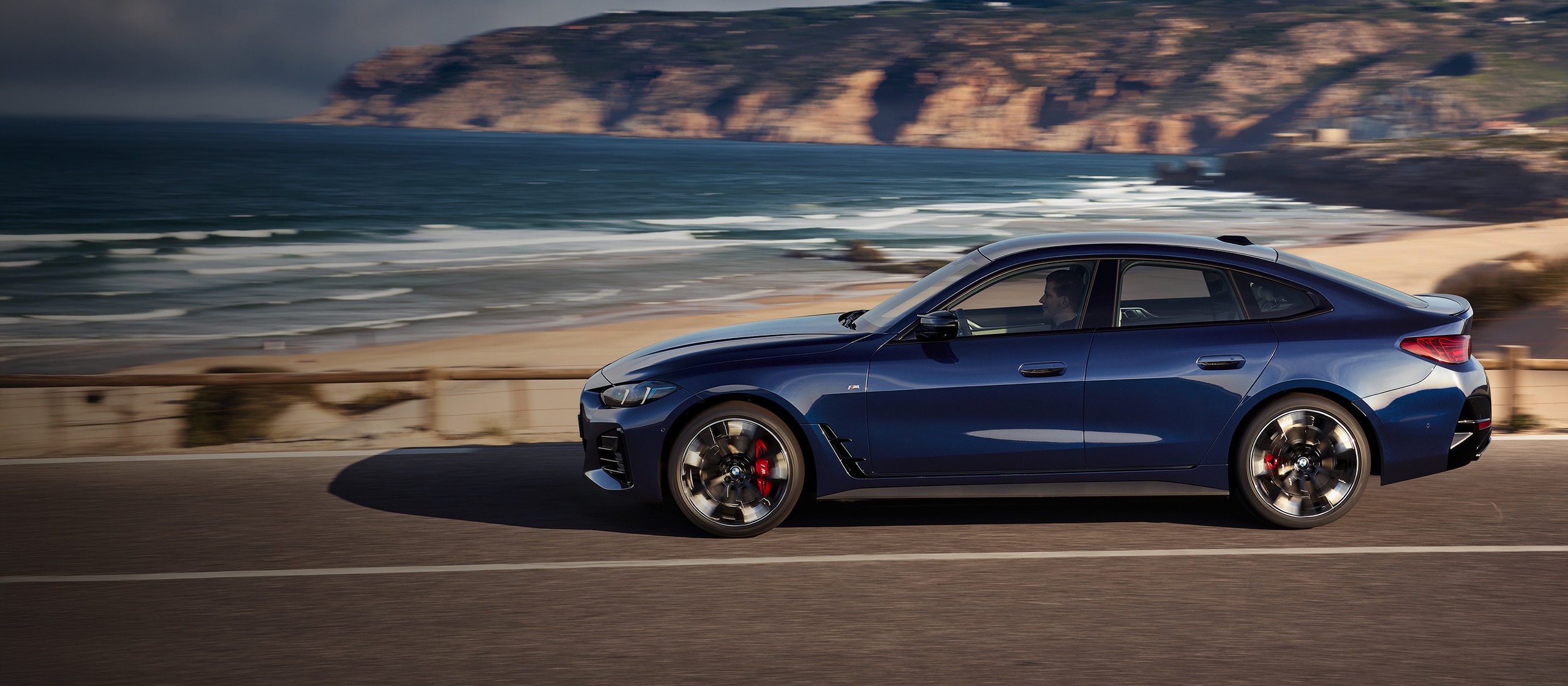 Blauer BMW auf einer Küstenstraße